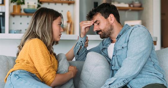 Worried couple talking together in the living room at home.