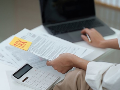 Parent reviewing tax documents with calculator and laptop.