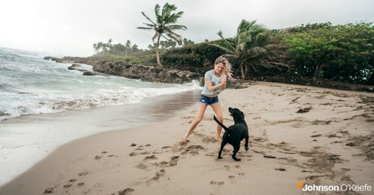 woman playing with her dog on a beach