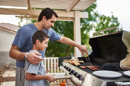 father and son grilling hotdogs